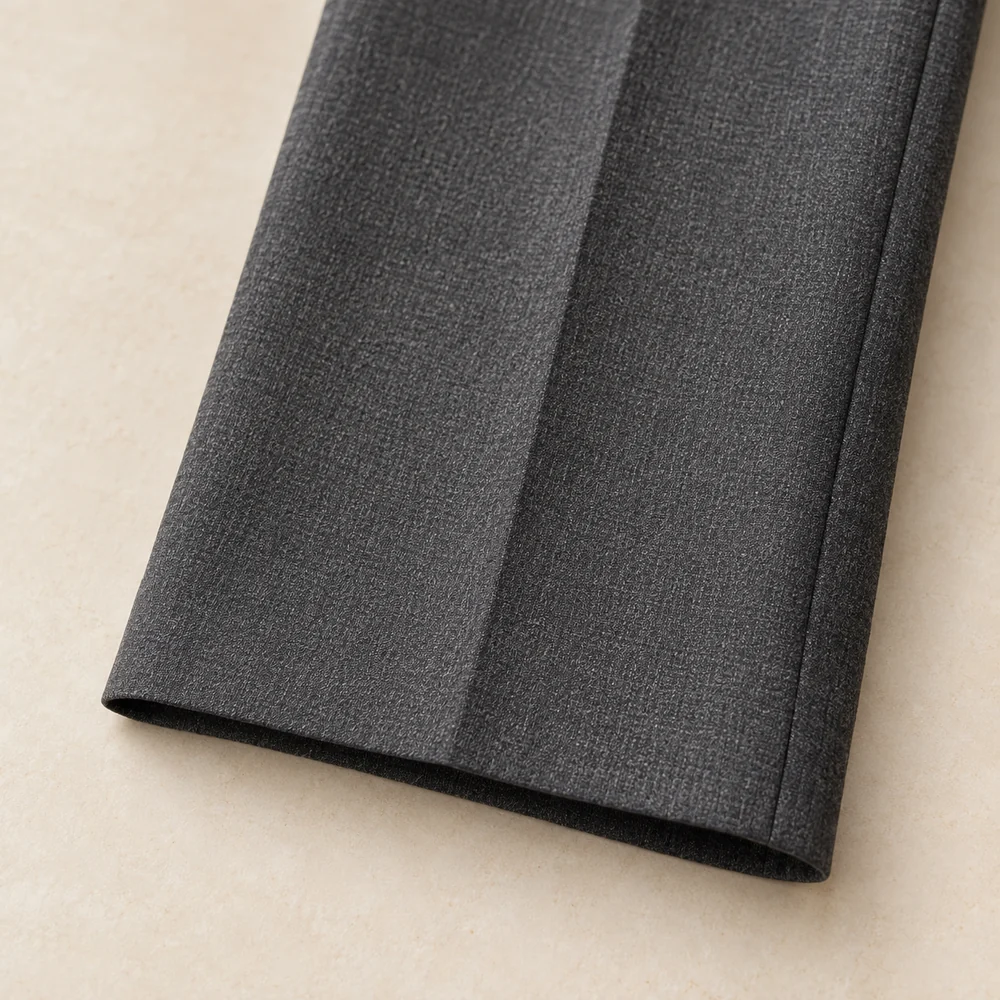 Détail d’un ourlet invisible sur un pantalon gris.