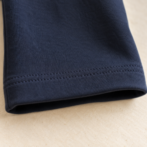 Illustration d’un ourlet à deux piqûres parallèles sur un pantalon bleu marine en tissu extensible.