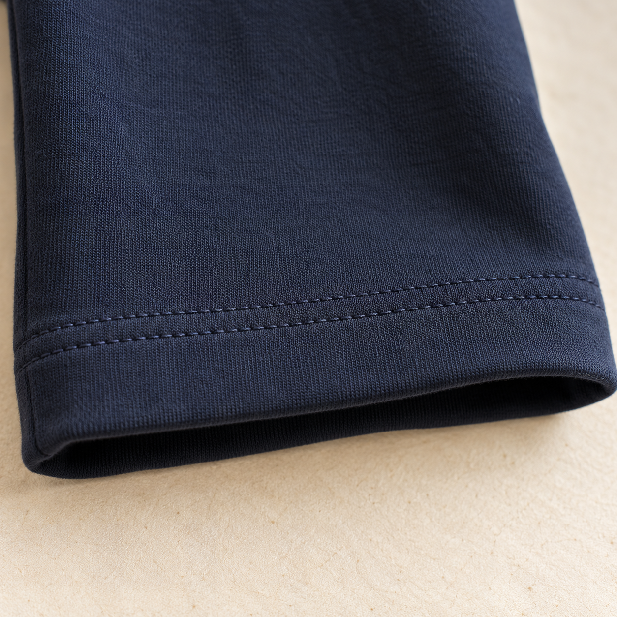 Illustration d’un ourlet à deux piqûres parallèles sur un pantalon bleu marine en tissu extensible.